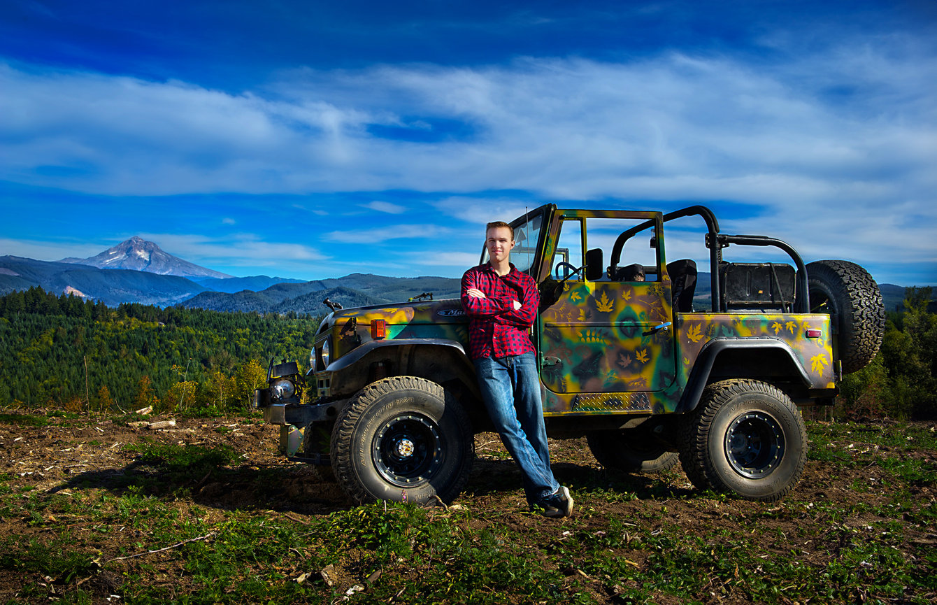 Woman leaning on a Jeep with mountains in the background.