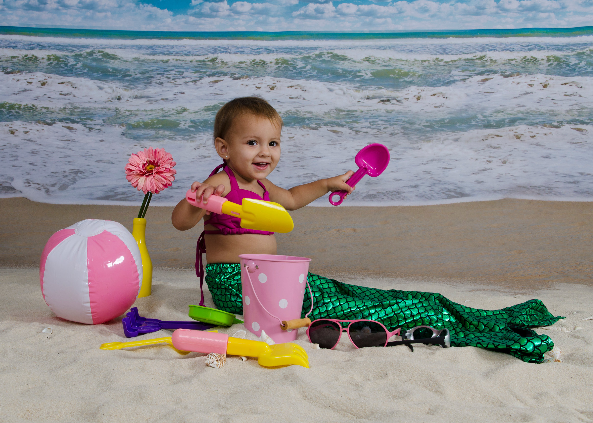 baby in sand dressed as a mermaid