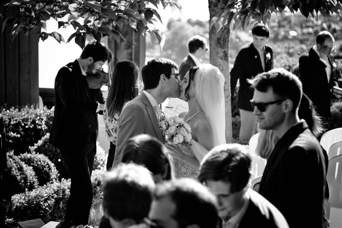 Crowd of people socializing outdoors, with a man in sunglasses in the foreground.
