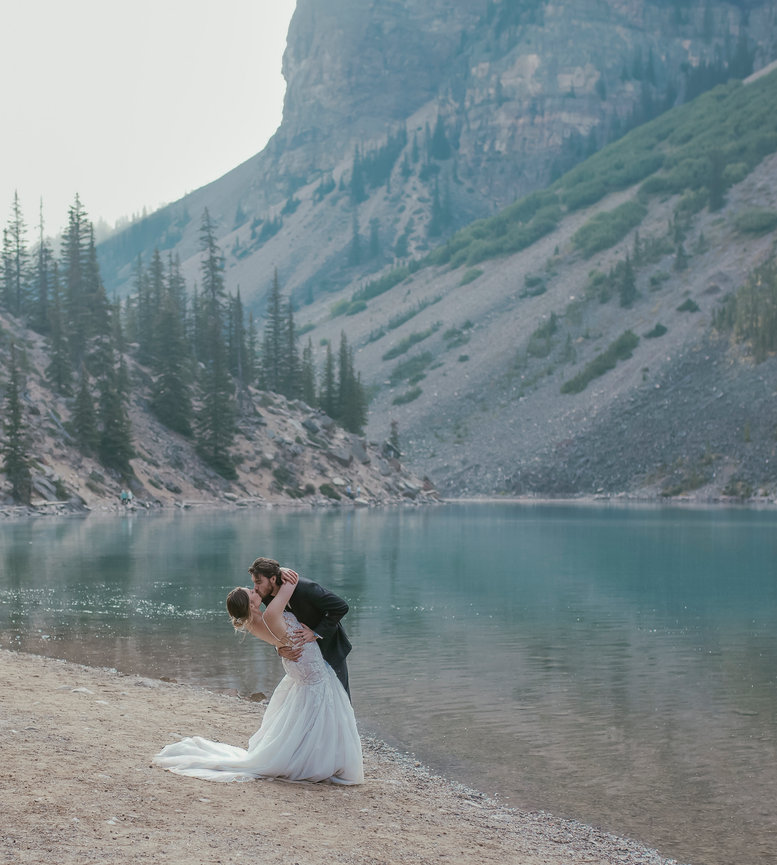 Couple embracing on a lakeshore with mountains behind