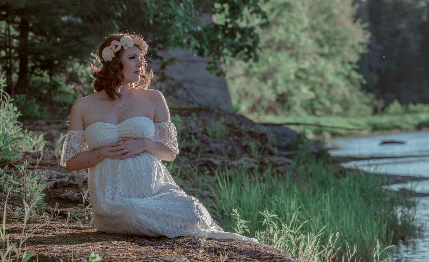 Woman in white dress sitting by a lakeside