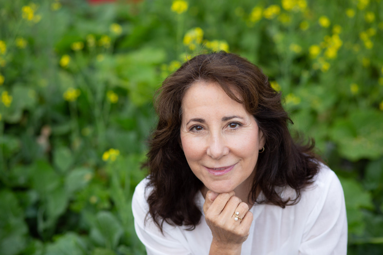 Woman in front of a bush with her hand under her chin in San Francisco.