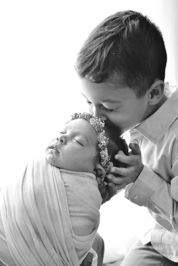 sibling kissing his newborn baby