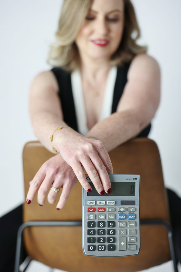 Woman leaning on a chair with a large calculator in the foreground. personal branding photos Melbourne