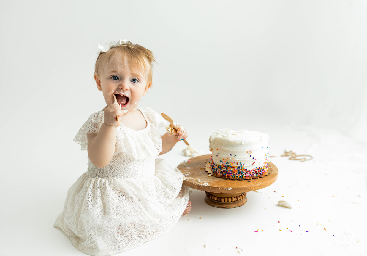 One-year milestone portrait with baby in festive outfit and custom cake setup