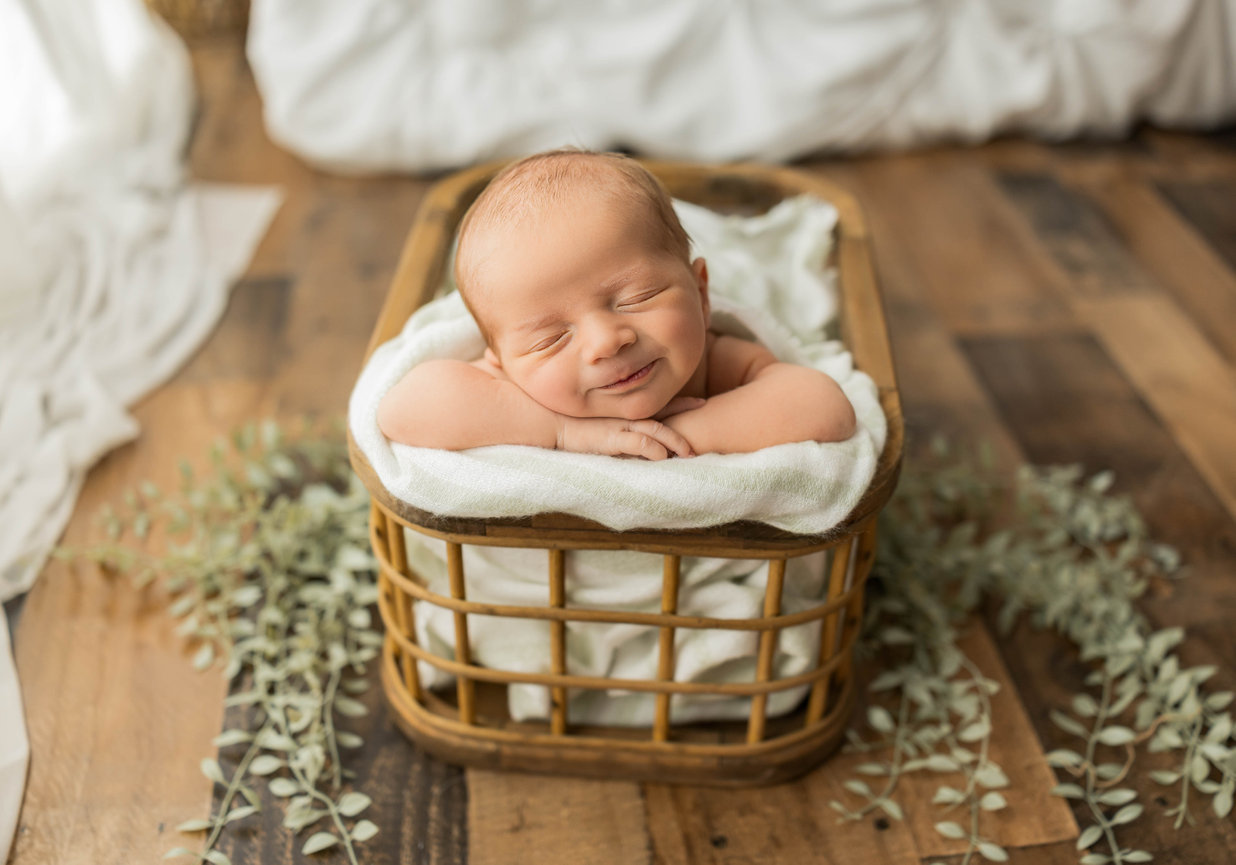 Newborn wearing knit hat resting hands under chin