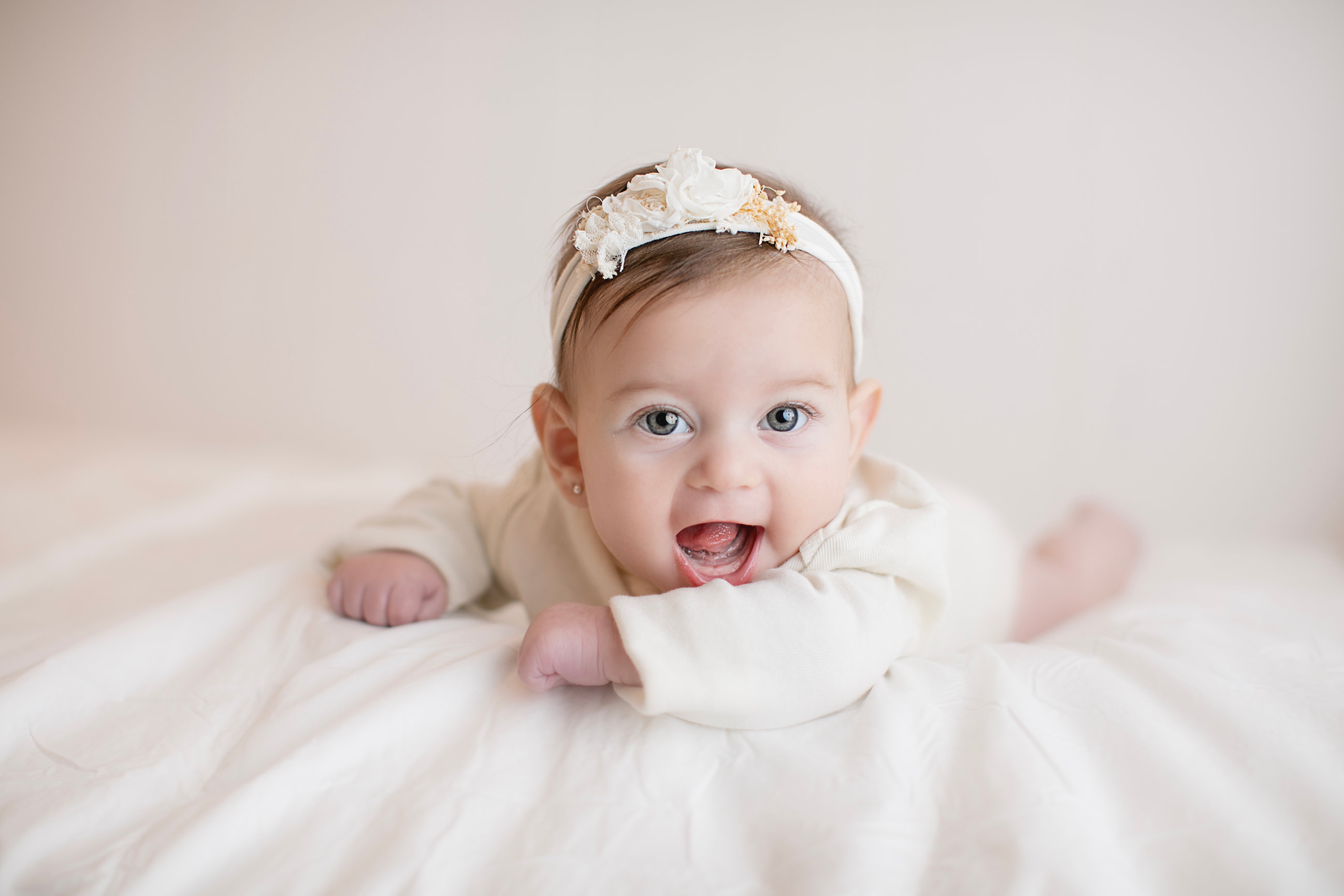 Baby lifting their head on a soft cream blanket