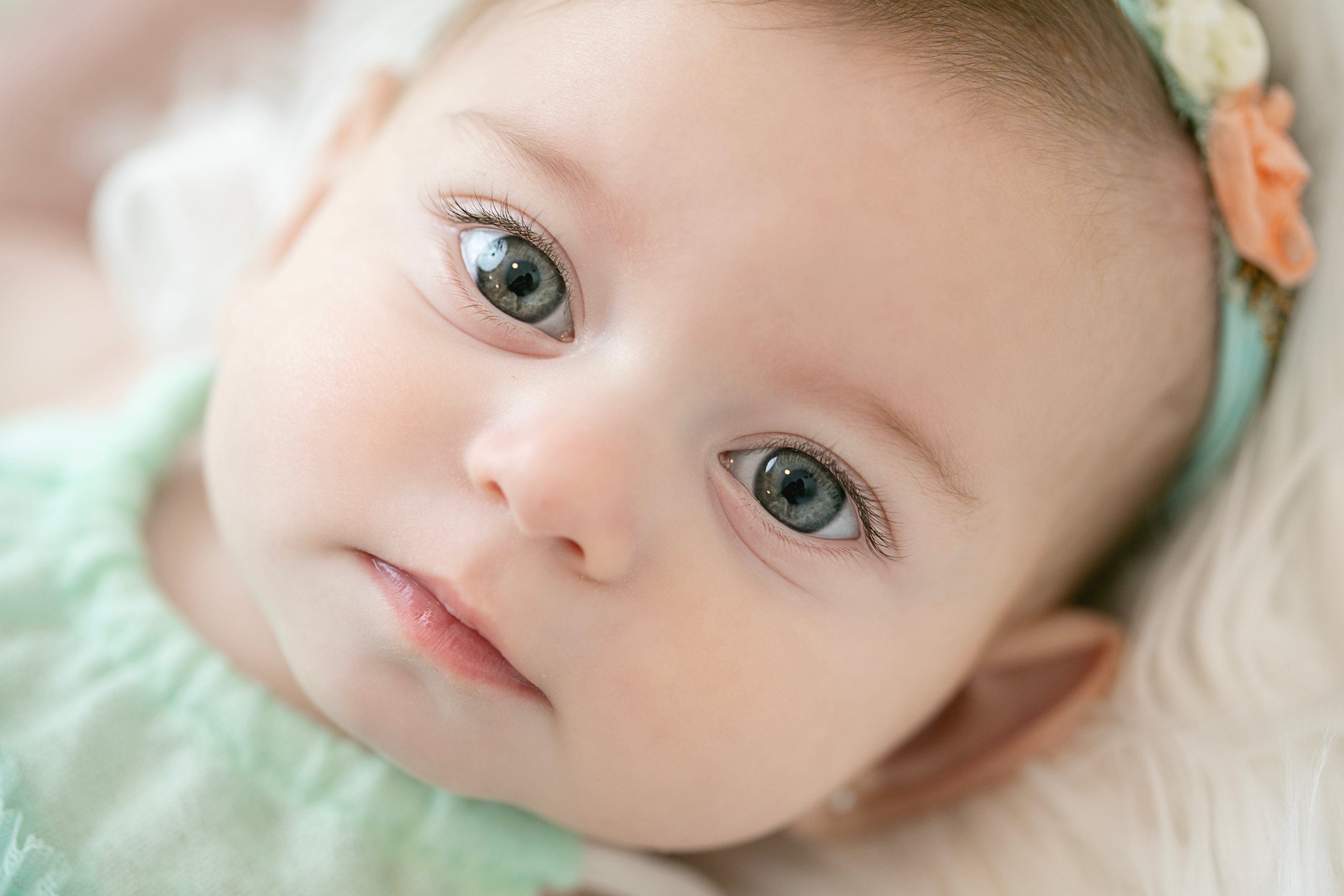 Baby looking towards the camera in mint green and cream