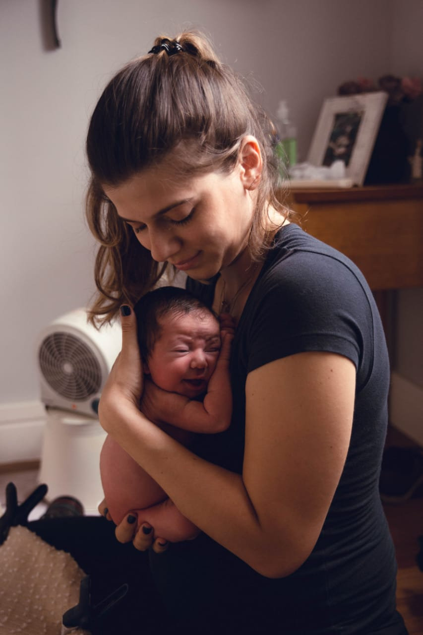Newborn gently cradled against a woman’s chest