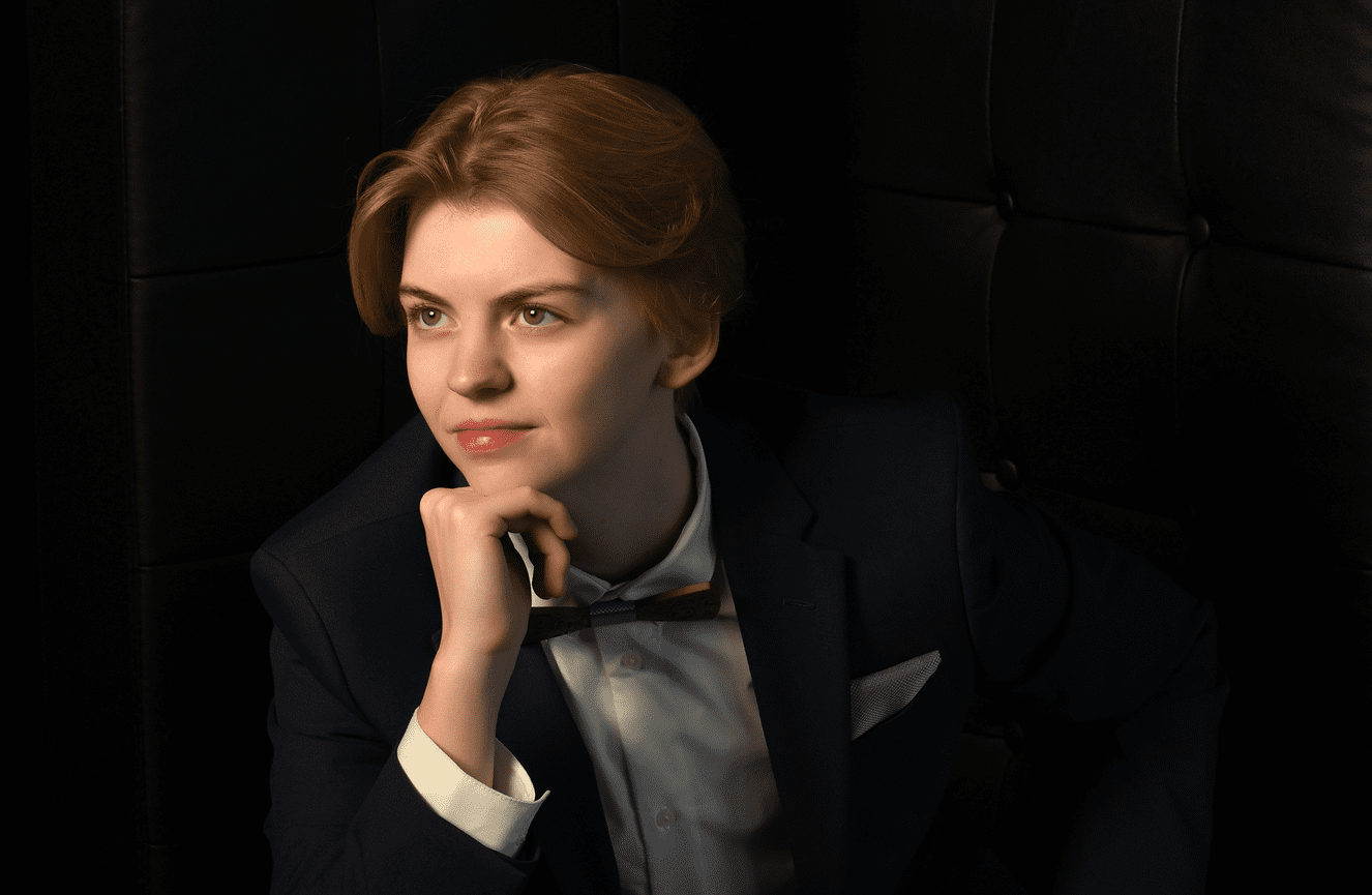 A high school senior wearing a bow tie looks reflective.