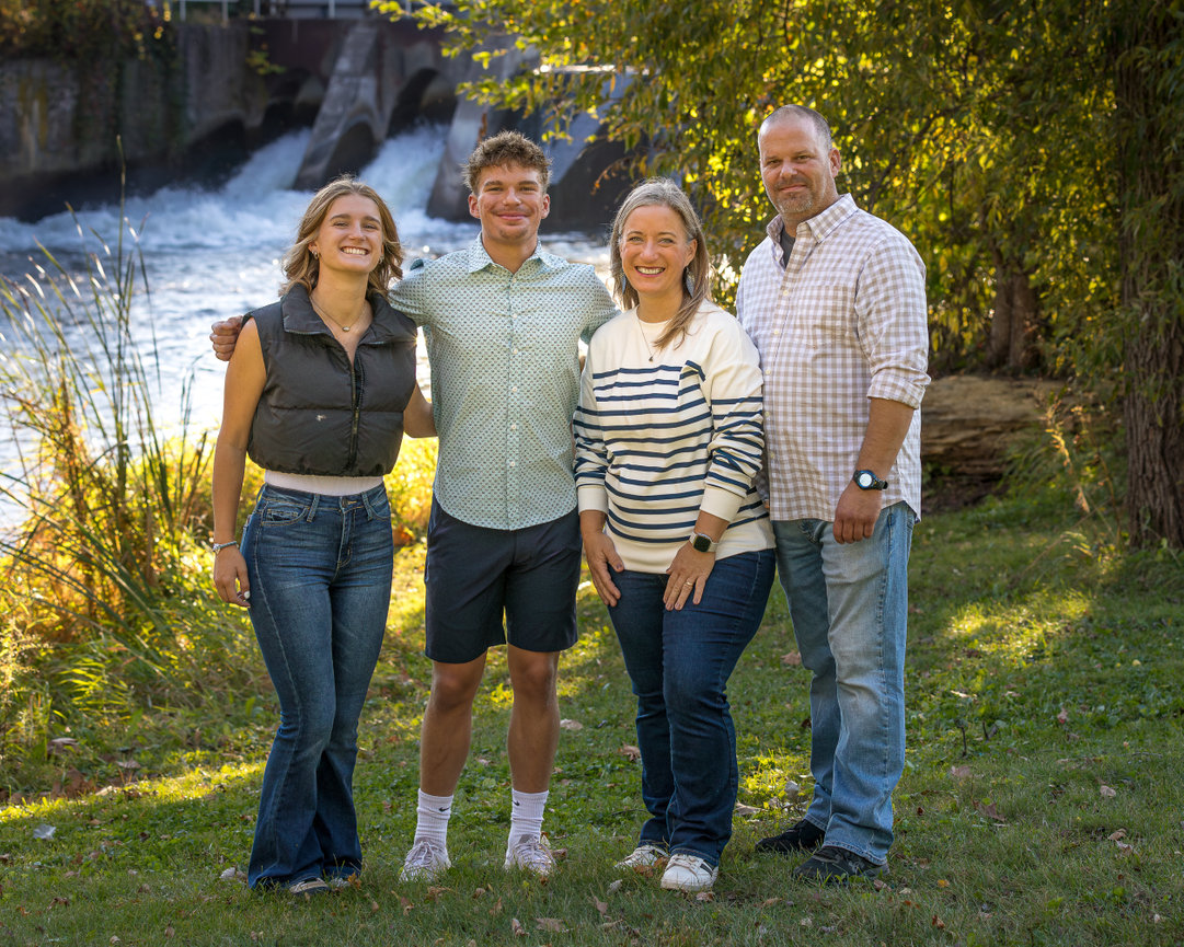 Family of four standing in front of a waterfall in a park