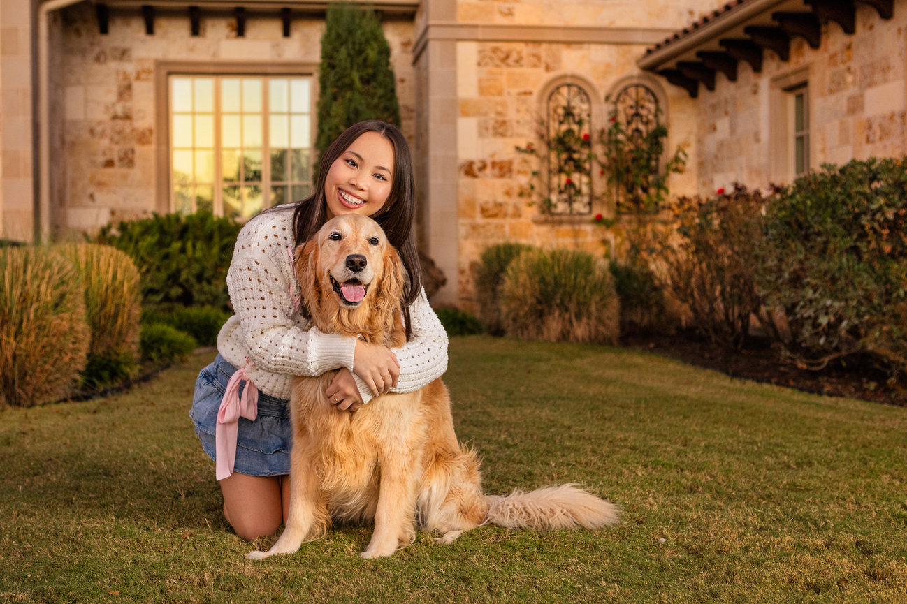 Yound girl hugging her dog for her senior portrait session at her hous.