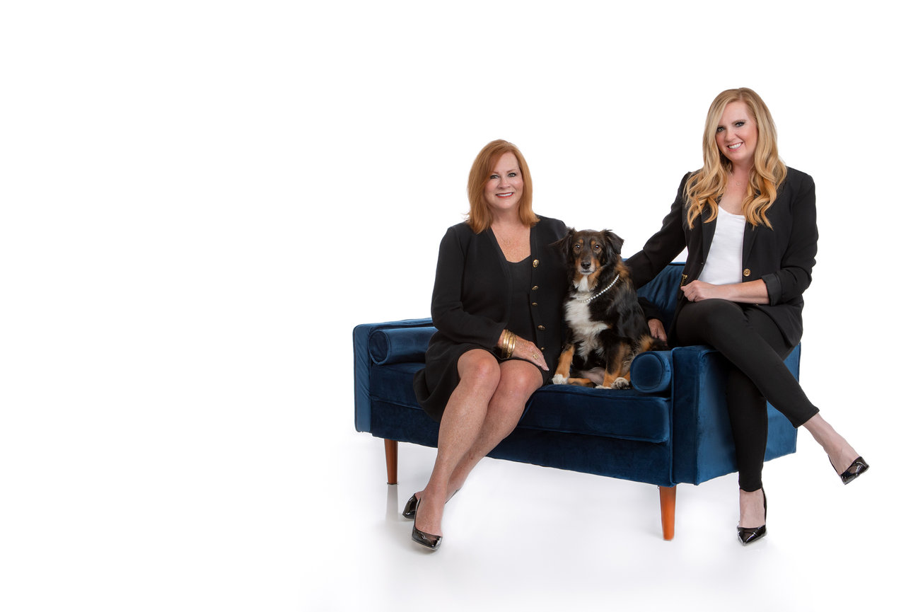 Family portrait in studio with their dog on a couch.