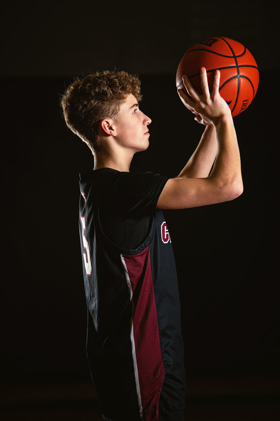 Westosha Central High School basketball player in a black uniform preparing to shoot a basketball against a dark background for his senior pictures