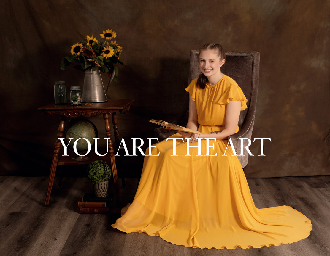 Person in a flowing yellow dress sitting on a chair with sunflowers on a table. Text overlays the image.