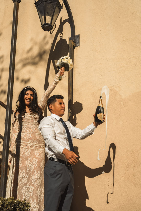 Couple celebrating by popping a champagne bottle outdoors